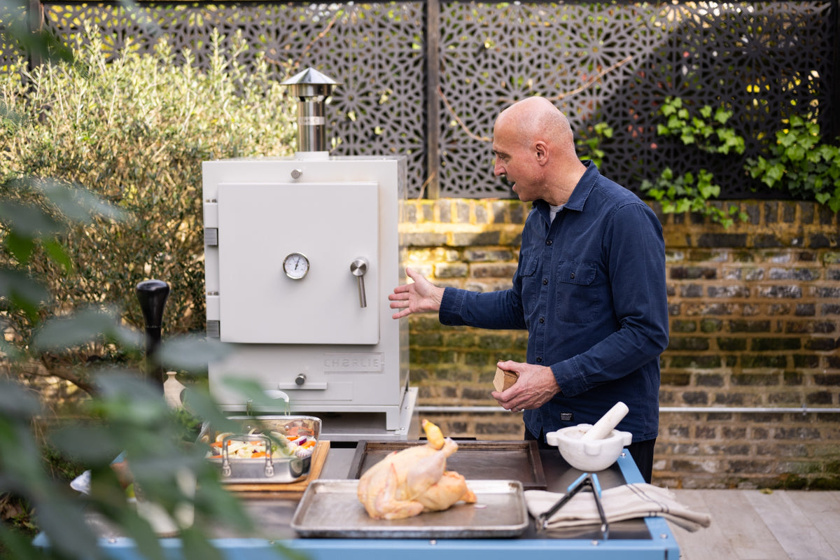 A member of the Charlie team showing a white Charlie oven in a garden
