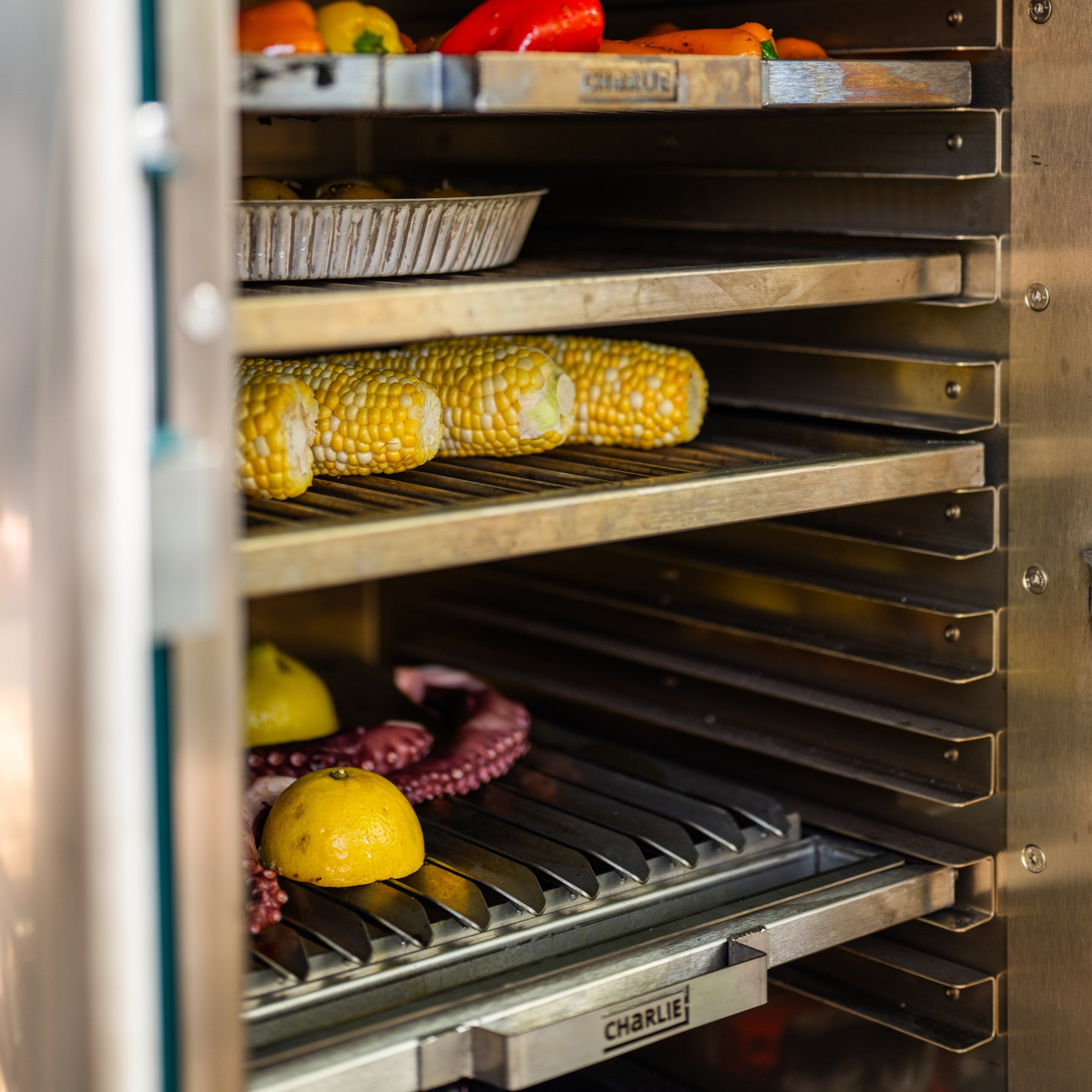 Stainless steel bbq appliance with shelves holding vegetables.