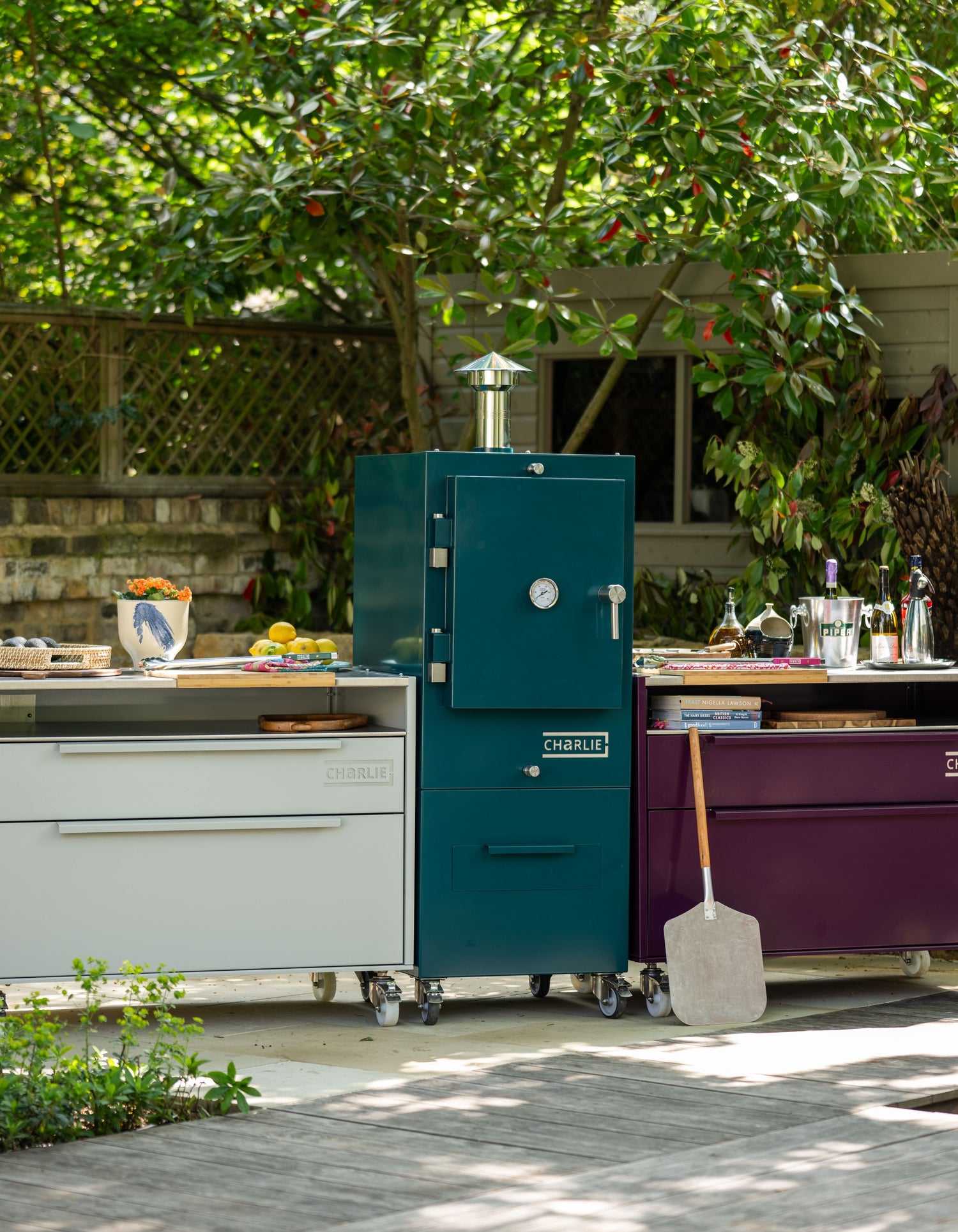 Teal barbecue smoker on a patio with outdoor kitchen.