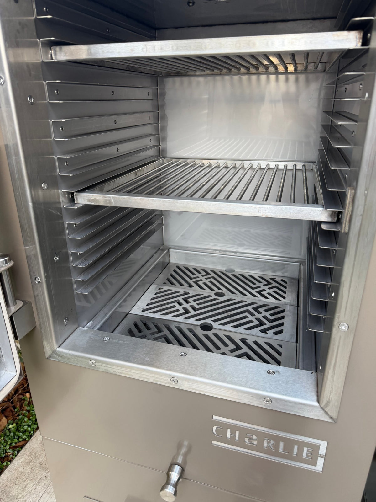 Charlie Charcoal Oven with the door open, showing a cooking rack above the patterned charcoal grates