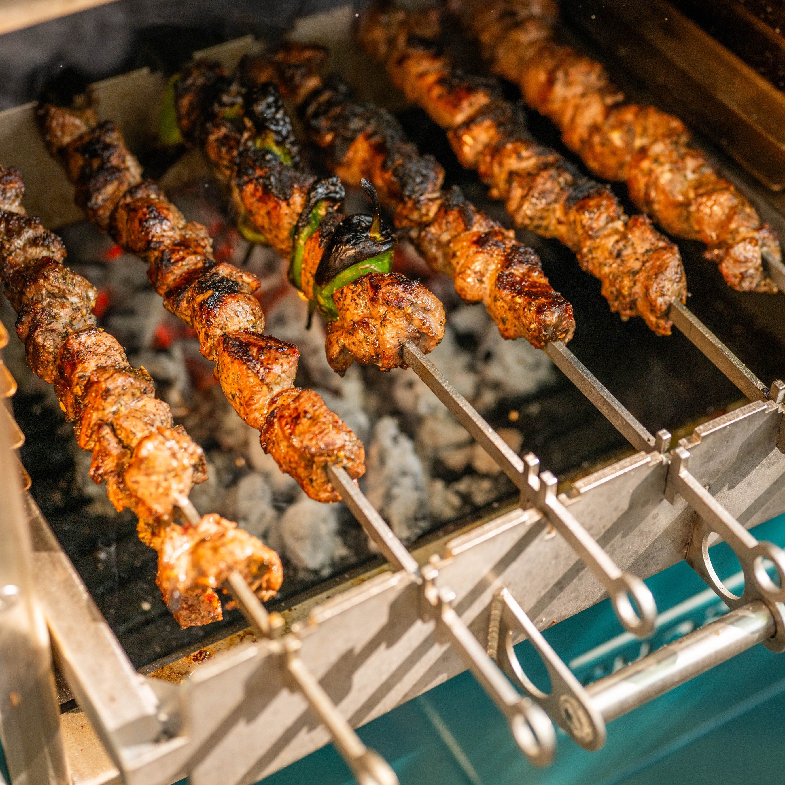 Skewers of grilled meat and vegetables on a barbecue grill.