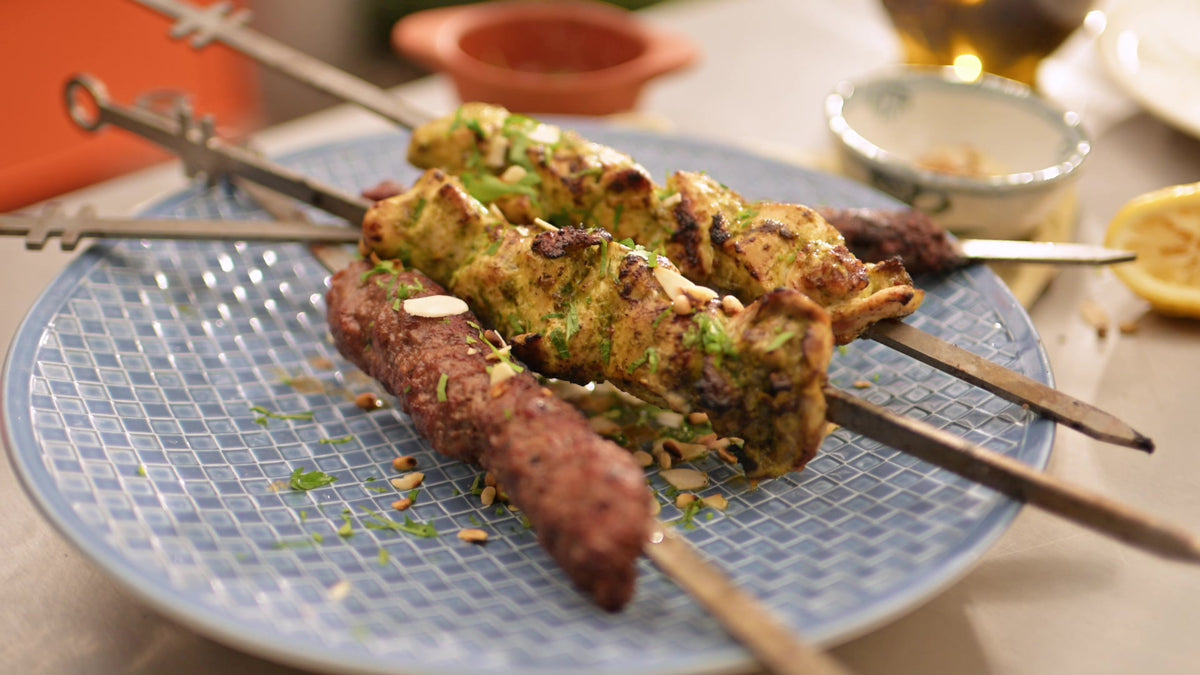 Chicken and lamb kebabs from the Charlie Oven on a plate with lemon and herbs