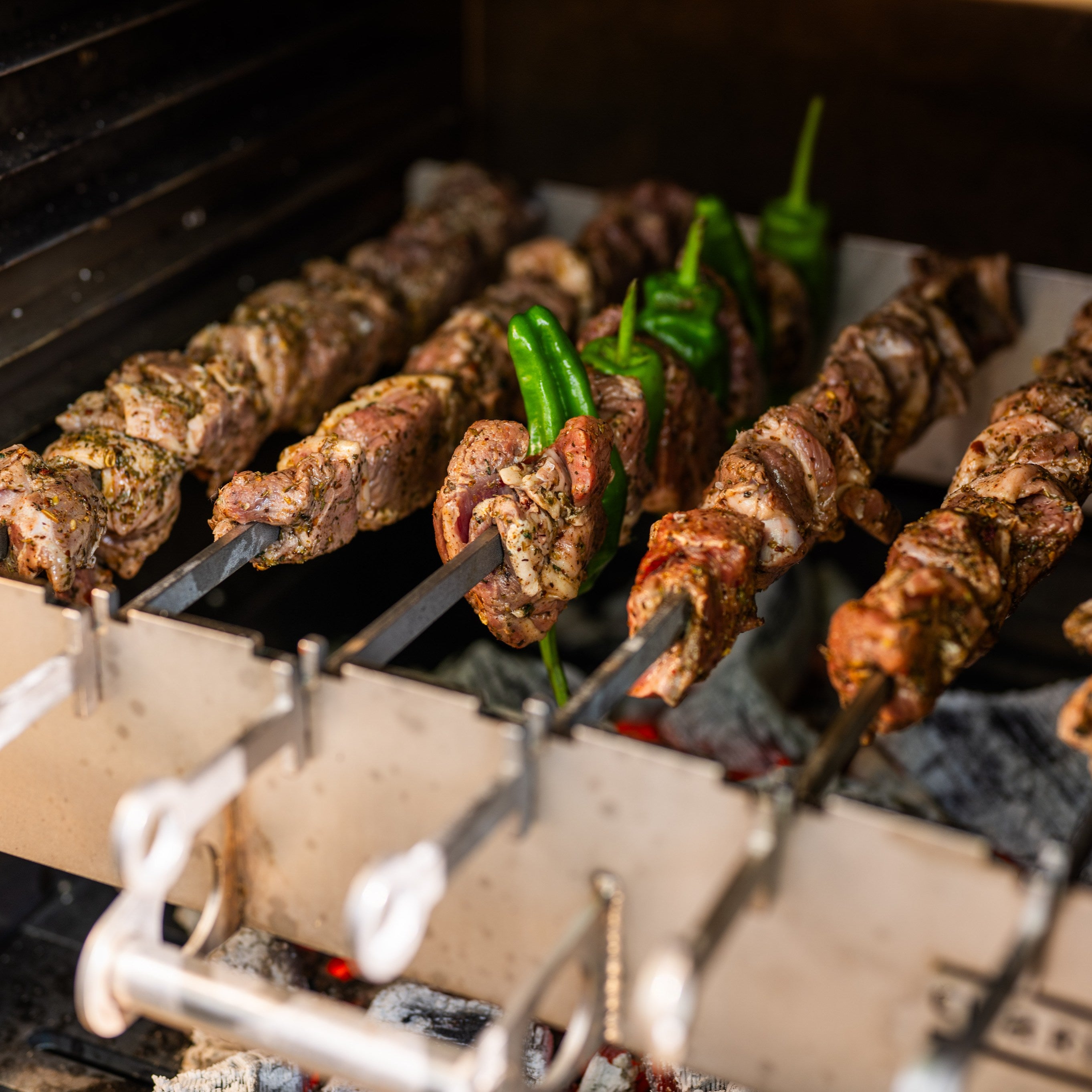 Skewers of meat and vegetables grilling on a barbecue.