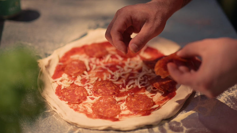 Topping a pizza with pepperoni