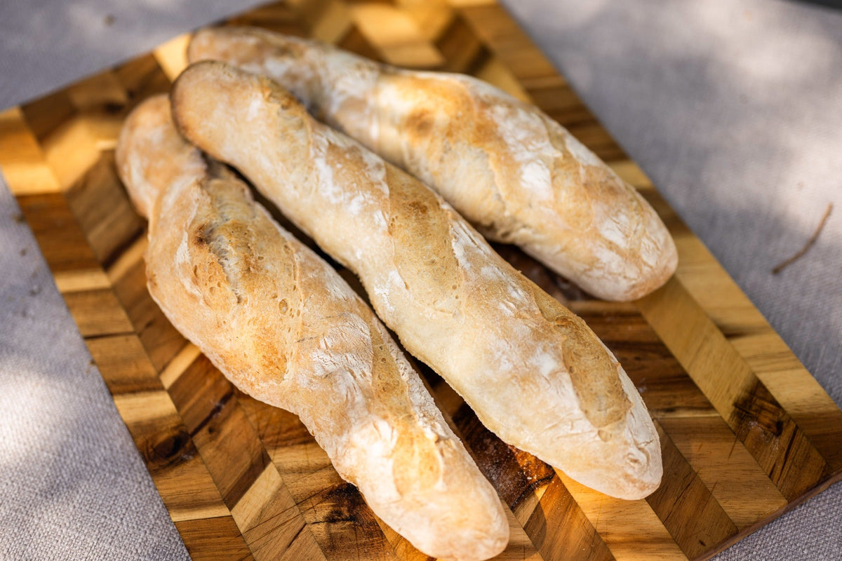 Three homemade baguettes on a wooden board