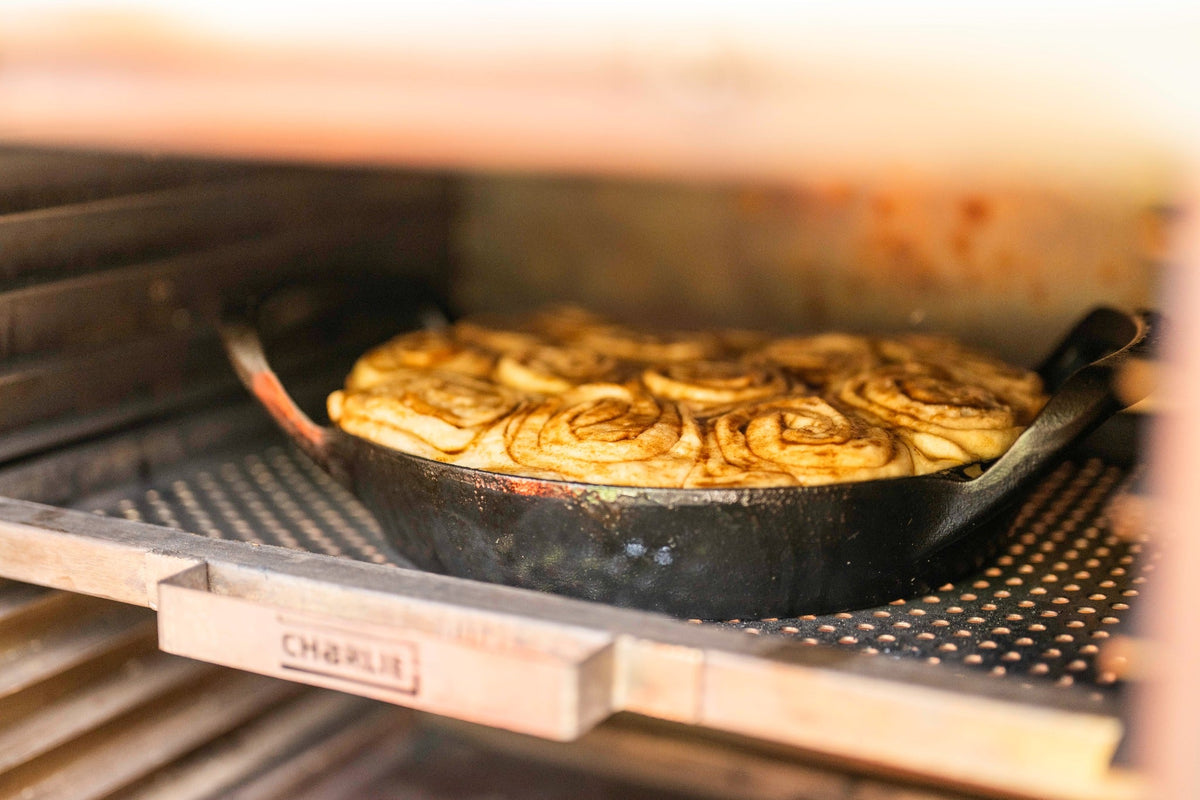 Cinnamon buns baking in a cast iron pan inside a Charlie Oven