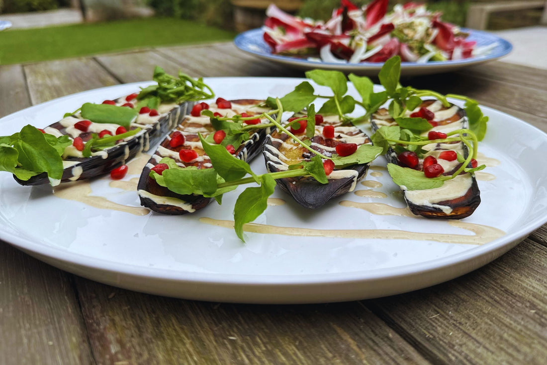 Baked aubergines topped with tahini, pomegranate seeds and watercress