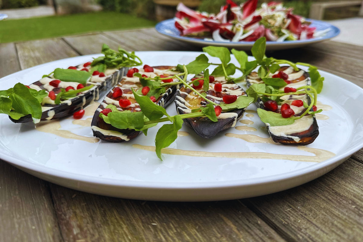 Baked aubergines topped with tahini, pomegranate seeds and watercress