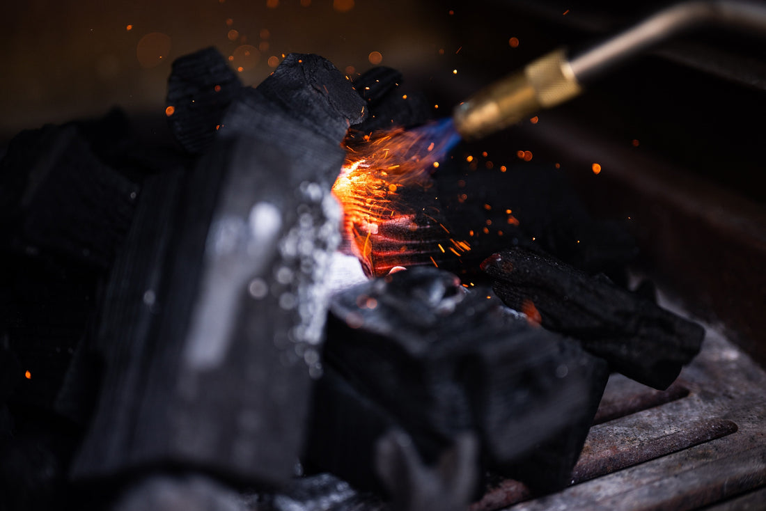 Lighting lumpwood charcoal on the fire grates of a Charlie charcoal oven.