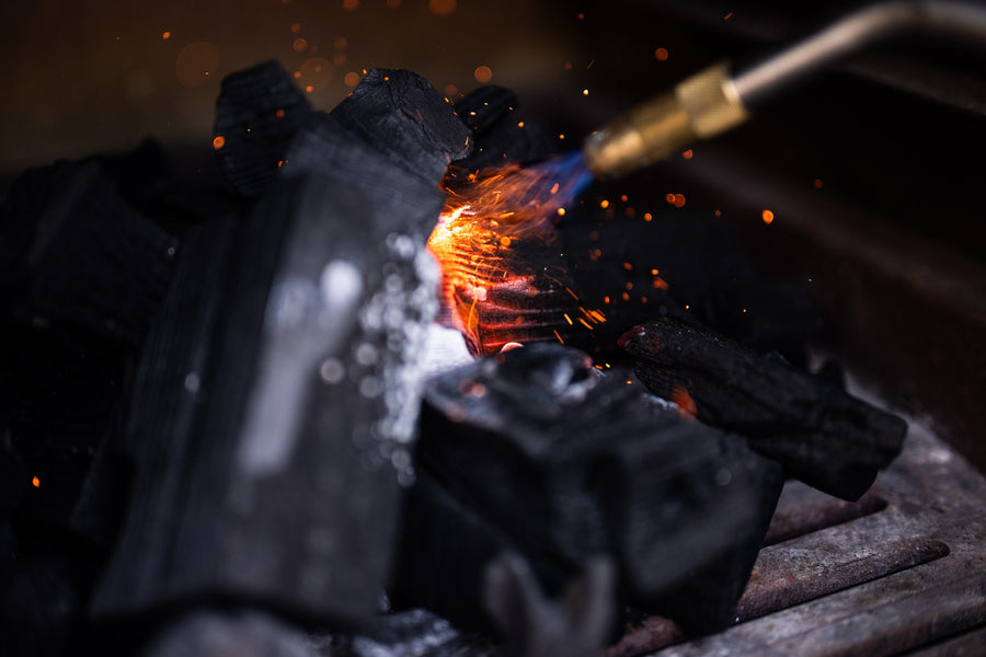 Lighting lumpwood charcoal on the fire grates of a Charlie charcoal oven.
