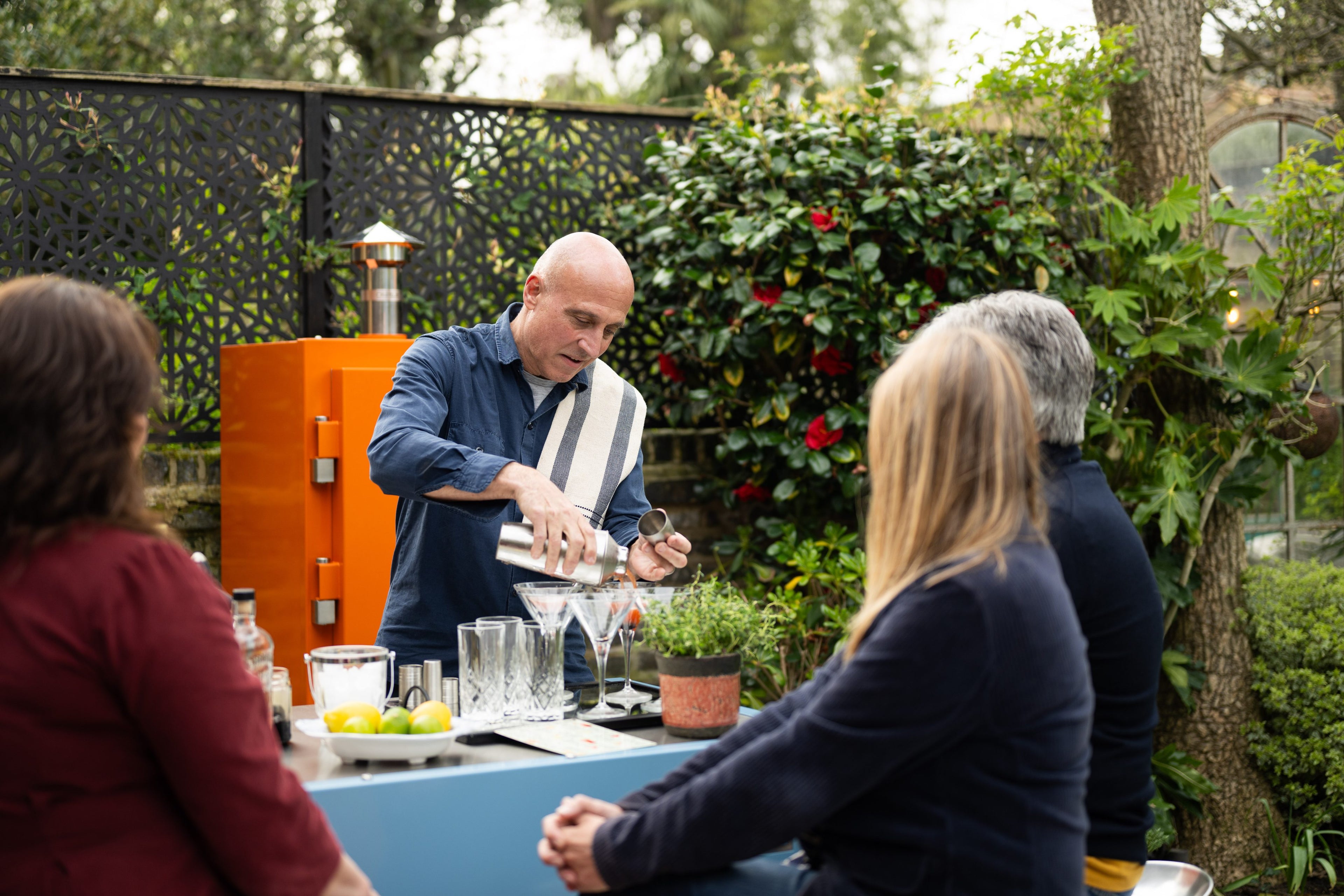 Man preparing drinks at a Charlie Kitchen Cabinet outdoors with people around