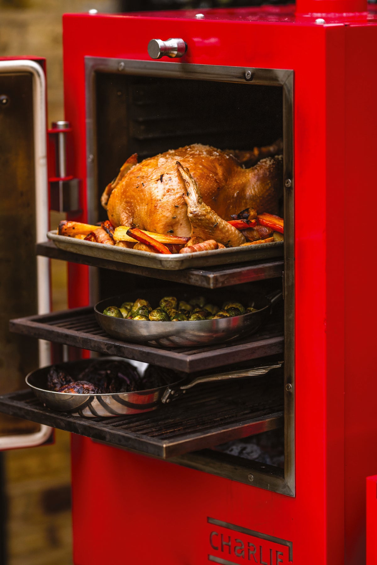 Several dishes cooking at once on different rack levels inside a Charlie Charcoal Oven