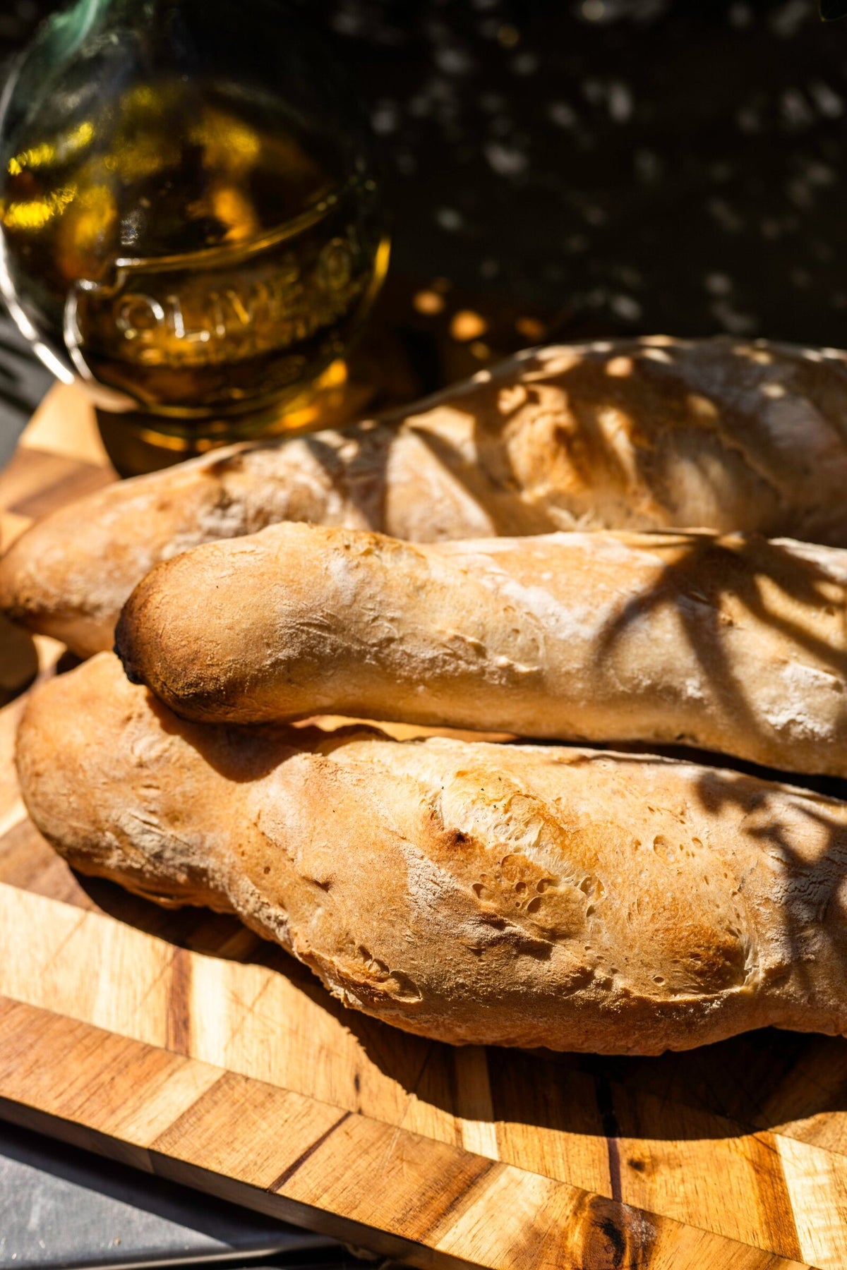Close up of baguettes baked over charcoal, with a bottle of olive oil behind