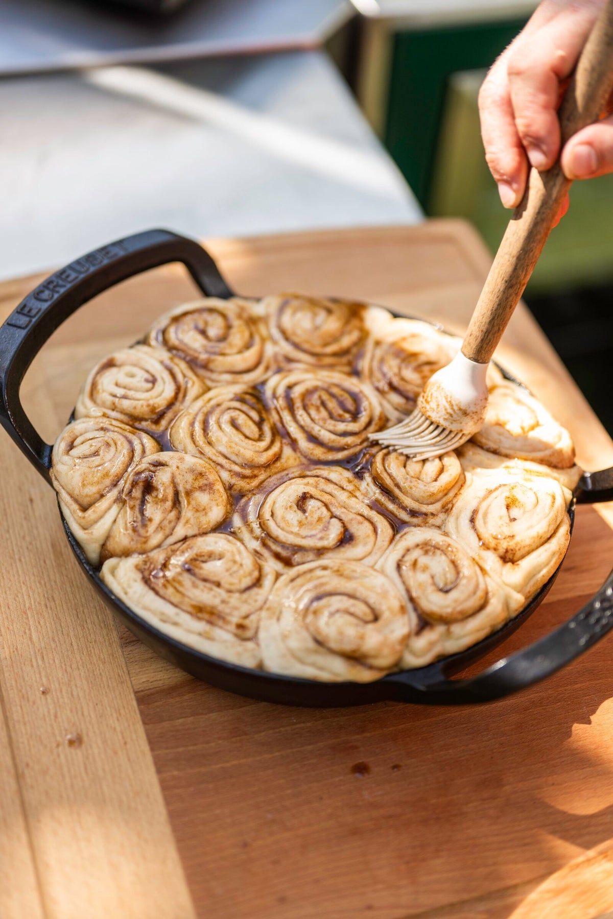 Brushing cinnamon buns with melted butter before they go into the oven