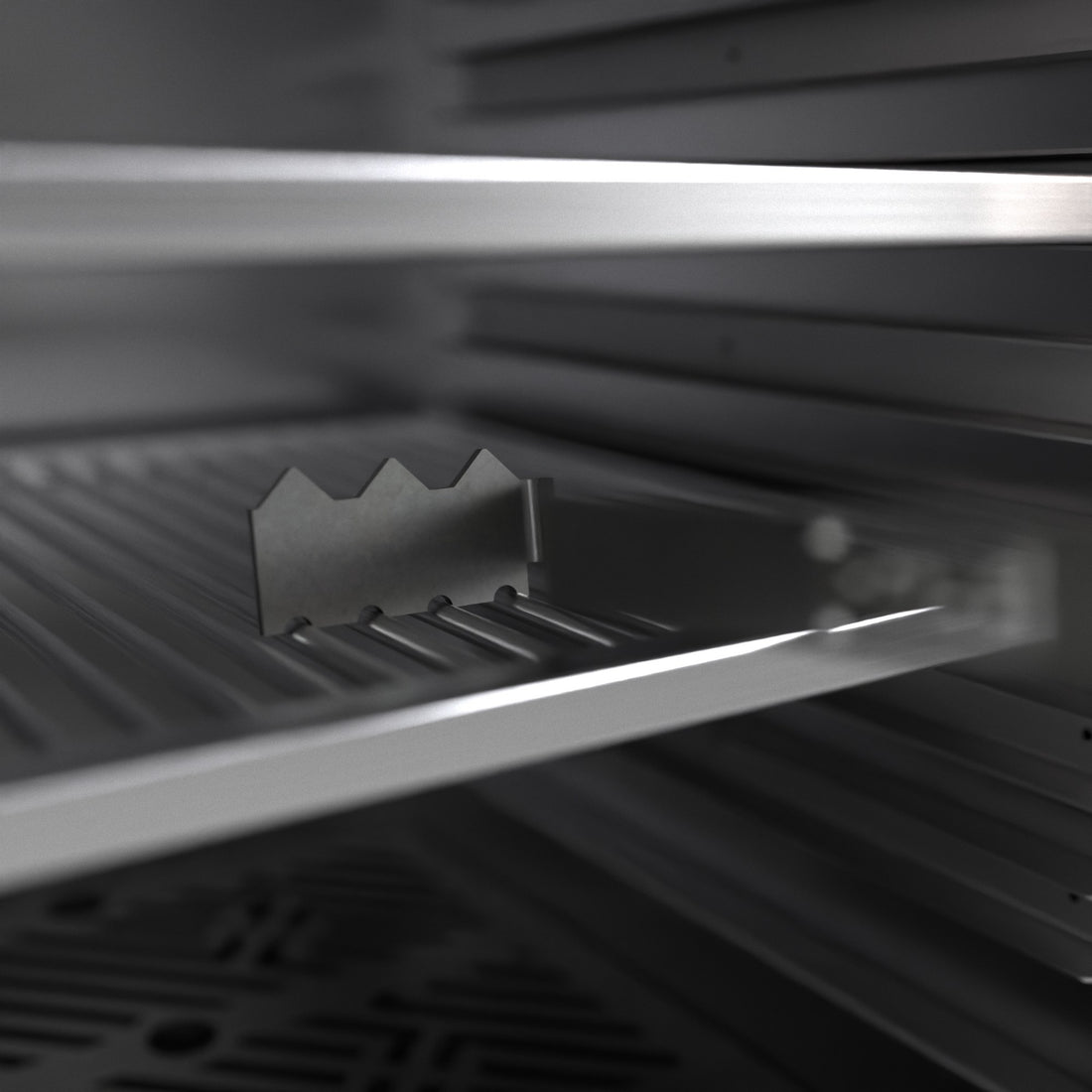 Charlie Oven charcoal rake and scraper inside a Charlie charcoal oven, its notched edge resting on the bars of the charcoal grate