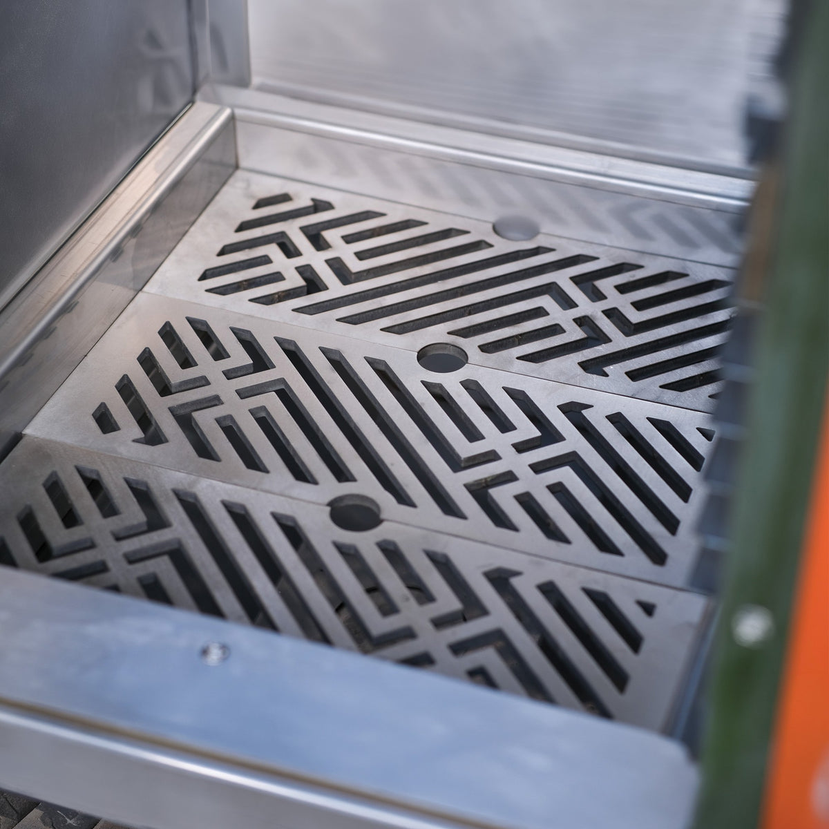 Patterned stainless steel charcoal grates with the Charlie signature design, fitted in a Charlie oven