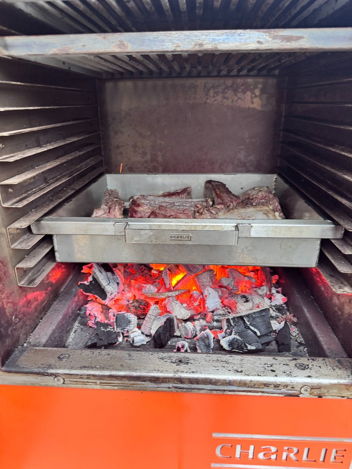 Charlie roasting tray cooking over lumpwood charcoal