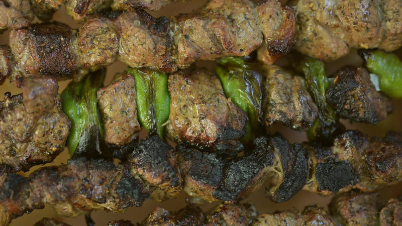 Close up of charred lamb and pepper kebabs on skewers