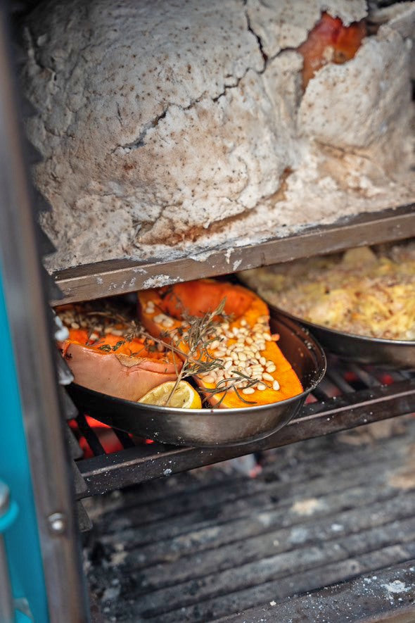 A salt-crust turkey on an upper level of a Charlie Oven, with squash and other sides roasting on the level below