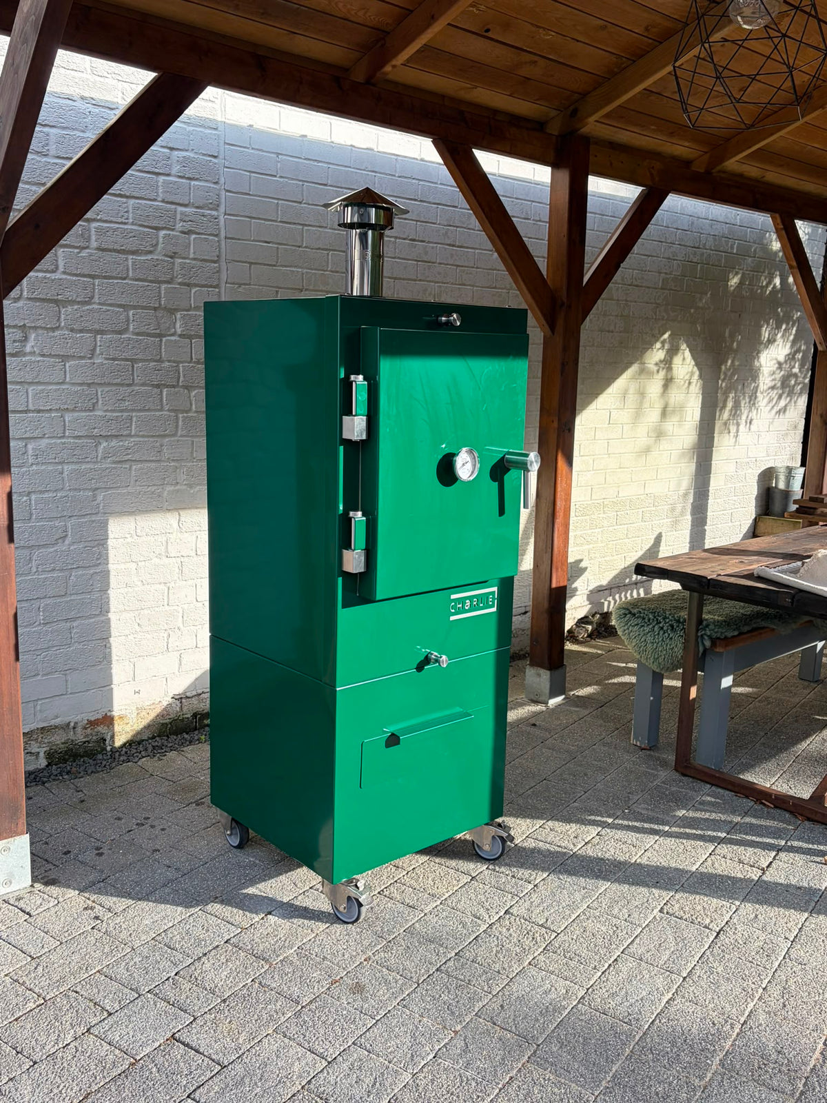 Charlie Charcoal Oven in green chilli under a wooden pergola, lifestyle view 