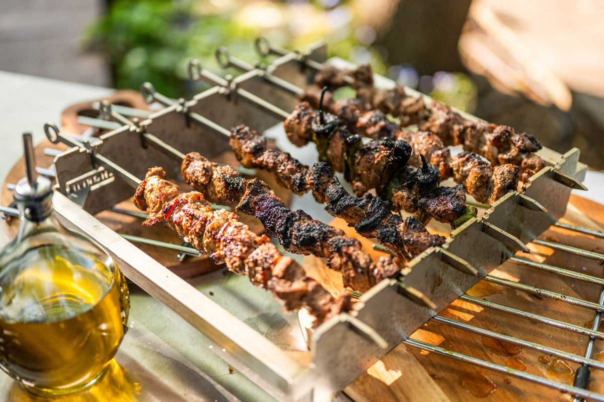 Charred lamb and pepper kebabs on the Turkish-Style Kebab Rack, out of the oven on a wooden board