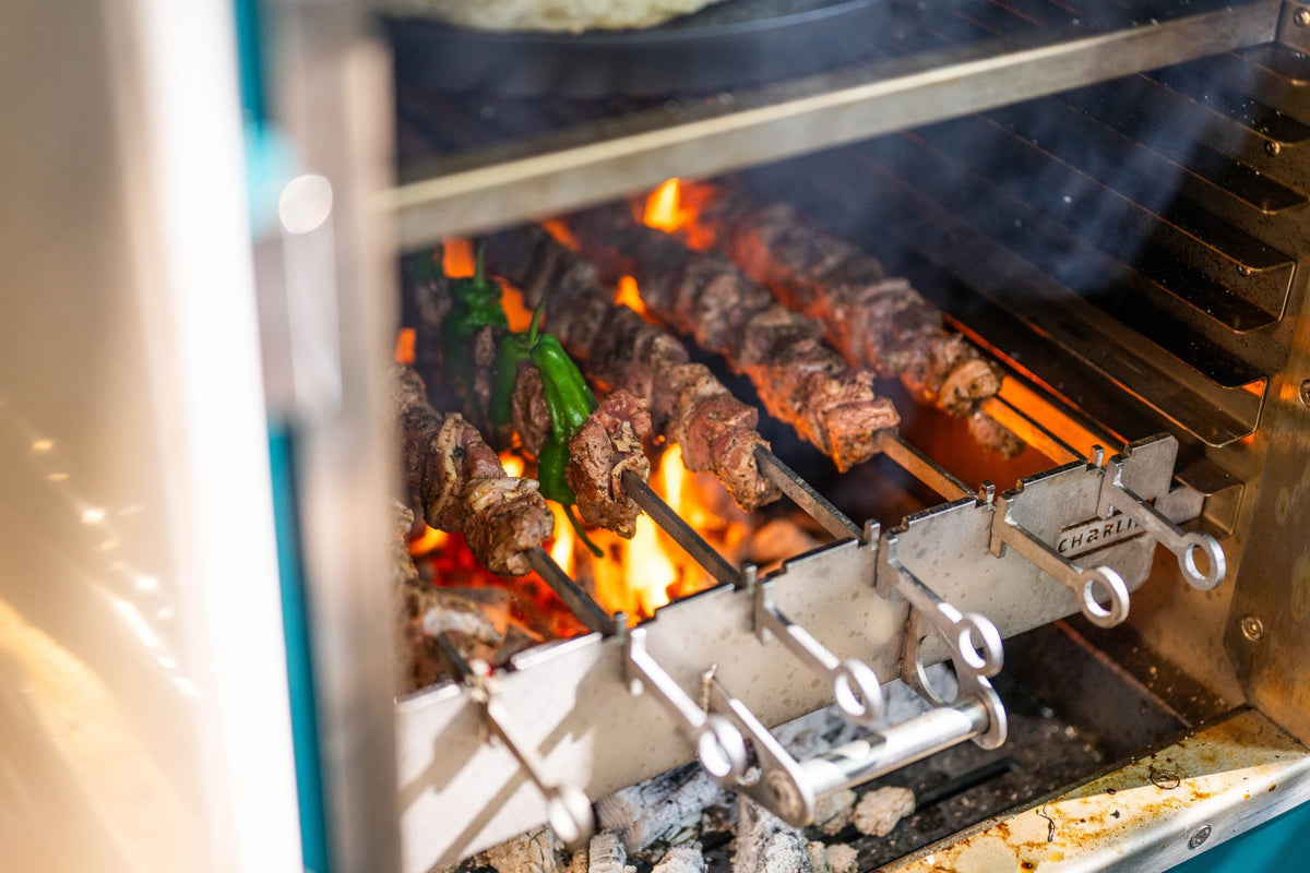 Lamb kebabs and green peppers over charcoal flames on the Charlie kebab rack