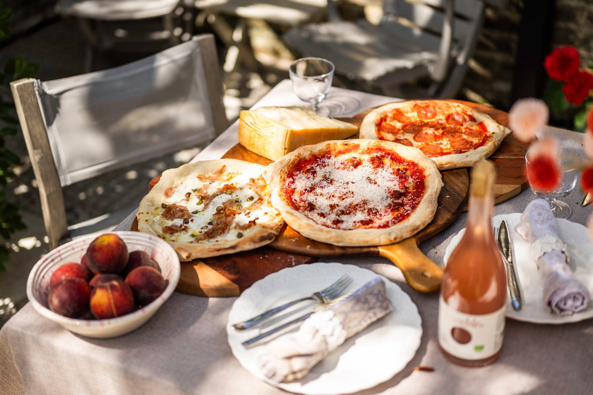 Pizzas, peaches and rosé on a garden table for a summer lunch