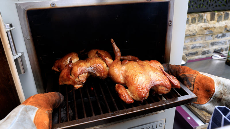 Two roast chickens coming out of a Charlie charcoal oven.