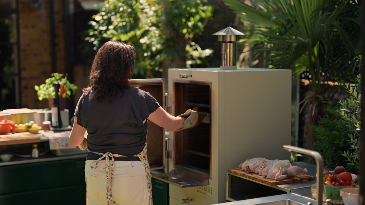 Loading a Charlie charcoal oven in a garden outdoor kitchen