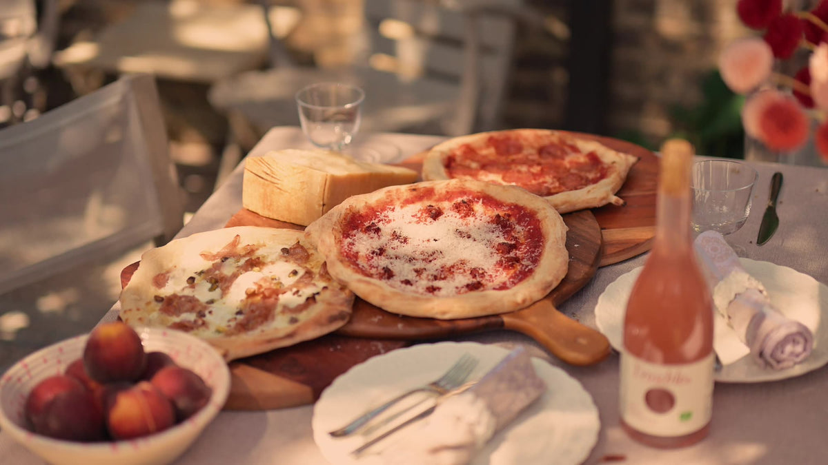 Three pizzas served on a garden table